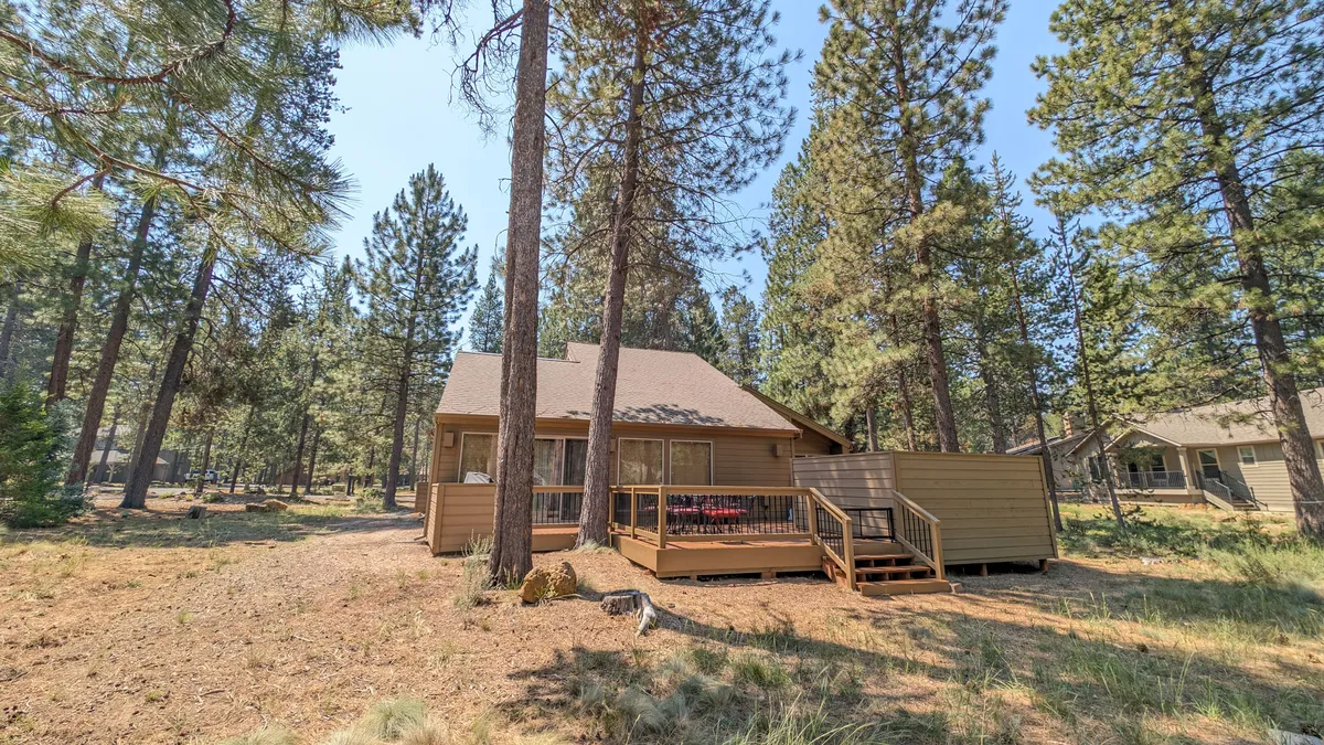 A tranquil wooden deck nestled among tall pine trees, showcasing the exterior of the cabin. The deck offers ample space for relaxing, socializing, and appreciating the surrounding natural beauty. There are no barriers, making it easy to access for guests of all ages and mobility levels.