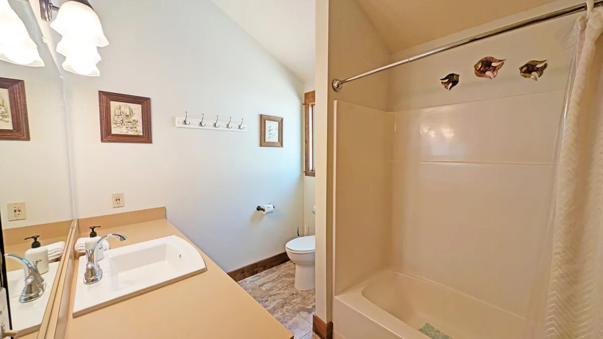 A bright and modern bathroom featuring a sink, shower area, wall decor, and a toilet. The space feels calm and refreshing, with thoughtful design elements for comfort and accessibility.