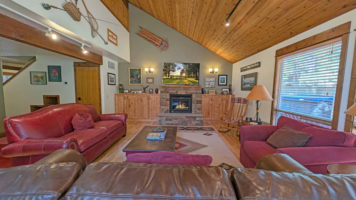 The hero image showcases a sunlit, inviting living room with plush sofas arranged around a modern fireplace, complemented by tasteful artwork above the mantel. The space exudes comfort and warmth, ideal for cozy family gatherings, quiet moments by the fire, or entertaining friends after a day of adventure.