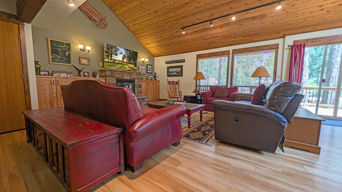 A bright living area highlighted by red leather sofas, a wooden coffee table, and large windows with beams on the ceiling. The space is bathed in natural light, suggesting a link to the outdoors and a welcoming environment for family gatherings or unwinding after adventures.